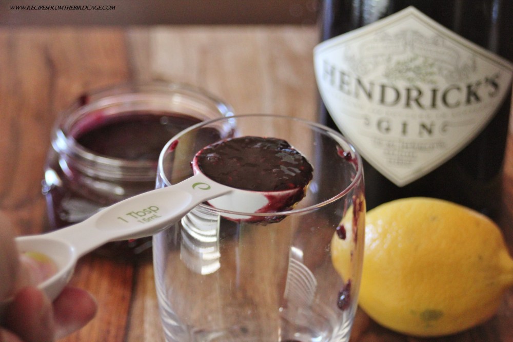 Berry puree is added to a glass.